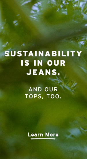 Image Description: The image background is a close up, blurred image of plants. There is white text that reads: 'Sustainability is in our jeans. And our tops, too.' Beneath is a clickable link directing you to 'Learn More.'